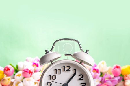 Photo for Spring Time Change flatlay. Summer back concept. White Retro Vintage alarm Clock with fresh, beautiful white spring flower on pastel green background, wide bouquet banner background copy space - Royalty Free Image