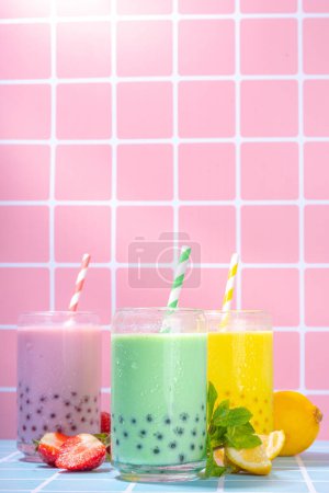 Photo for Set of three colorful summer bubble tea, bright creamy pearl tea or latte tapioca drinks, pink berry, yellow citrus, green mint, with tapioca balls and crushed ice, on colorful tile background - Royalty Free Image