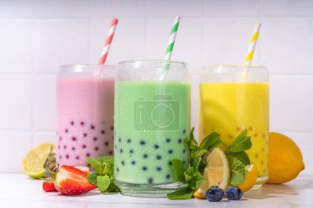 Photo for Set of three colorful summer bubble tea, bright creamy pearl tea or latte tapioca drinks, pink berry, yellow citrus, green mint, with tapioca balls and crushed ice, on white background - Royalty Free Image