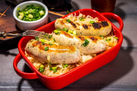 Photo for White fried Munich, wurst sausages with fried cabbage or sauerkraut. Oktoberfest, Bavarian summer grill party food portion, with fresh herbs and tomato bbq sauce - Royalty Free Image