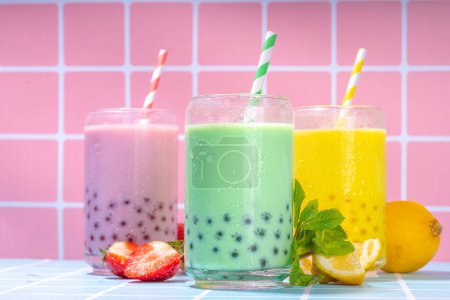 Photo for Set of three colorful summer bubble tea, bright creamy pearl tea or latte tapioca drinks, pink berry, yellow citrus, green mint, with tapioca balls and crushed ice, on colorful tile background - Royalty Free Image
