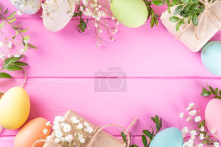 Foto de Pink Easter greeting card background with spring flowers, green leaf branches and colorful pastel Easter eggs, top view copy space - Imagen libre de derechos