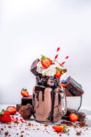 Photo for Double chocolate taste milkshake. Crazy shake with brownie taste, chocolate sauce, whipped cream topping and fresh strawberry, summer sweet loaded sweet dessert drink copy space - Royalty Free Image