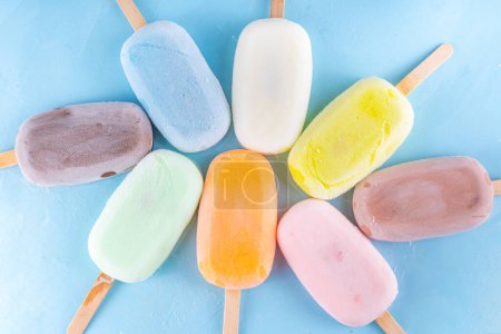 Photo for Selection of multicolored ice cream popsicles. Various flavor gelato, frozen lollypops - chocolate vanilla blueberry strawberry pistachio orange, on light blue background - Royalty Free Image