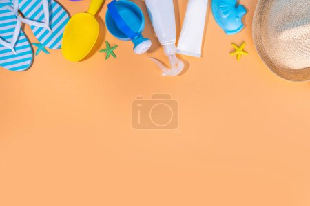 Téléchargez les photos : Enfants, enfants, protection bébé et soleil, soins de la peau anti-UV crème solaire cosmétique. Écran solaire SPF bouteille crème, lunettes de soleil, chapeau panama, moules de sable jouets sur fond beige ensoleillé - en image libre de droit
