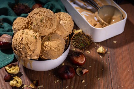 Téléchargez les photos : Crème glacée épicée d'automne au goût de châtaignier rôti, avec des épices, sur un fond en bois avec des châtaignes fraîches et rôties - en image libre de droit
