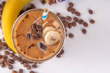 Blended banana coffee. Cold latte coffee and banana non-dairy, vegan diet drink with frozen bananas and espresso, on white kitchen table copy space