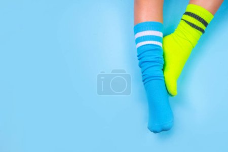 Photo for Odd Socks Day, Lonely Sock Day.  Anti-Bullying Week, Down syndrome awareness. Child legs wearing different pair of mismatched socks on high-colored background copy space - Royalty Free Image