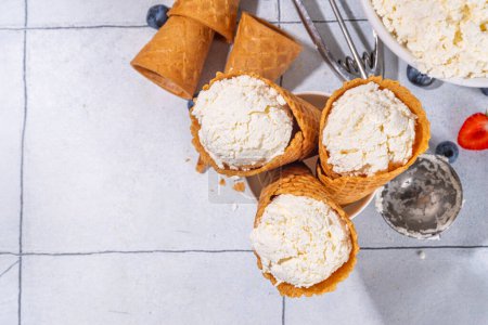 Téléchargez les photos : Glace au fromage cottage, crème glacée vanille au fromage cottage blanc tendance en cônes de gaufres, avec baies fraîches et garnitures - en image libre de droit