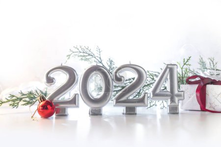 Téléchargez les photos : 2024 Fond de vacances du Nouvel An avec numéros 2024, boîte cadeau, décoration et boules d'arbre de Noël, lumières festives et sapin, espace de copie de fond en argent doré - en image libre de droit