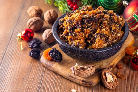Homemade Christmas sweet mincemeat bowl, dried fruit mince meat for traditional winter mince pies with cinnamon sticks, anise, with festive decorations and christmas tree branches