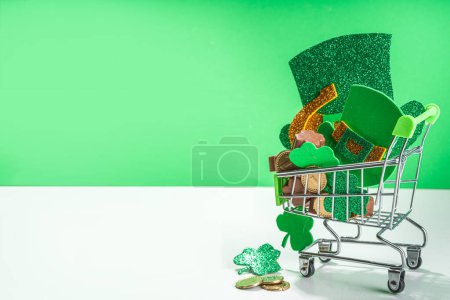 Foto de San Patricio fondo de venta, carrito de compras de supermercado con hojas de trébol de trébol, decoración de sombrero de duende, monedas de oro y chocolates en forma de símbolo del día de San Patricio - Imagen libre de derechos