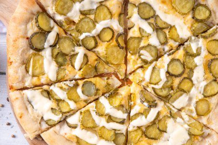 Pickle Pizza with cheese sauce and pickled cucumbers. Trendy asian style, vegan sour taste pizza on kitchen table copy space
