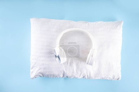 Sonic teintes et bruit pour le concept de sommeil avec écouteurs confortables et oreiller blanc sur fond bleu clair vue du dessus copier l'espace