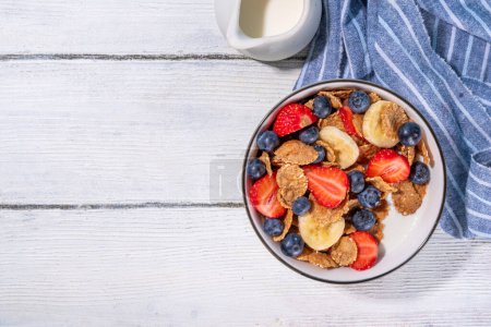 Téléchargez les photos : Alimentation saine en vitamines petit déjeuner d'été. Flocons de céréales multigrains avec yaourt ou lait et fraises, bleuets, sur la table de cuisine espace de copie - en image libre de droit