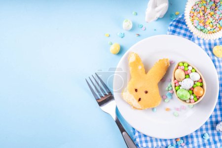 Food for Easter school lunchbox. Creative children's breakfast, pancakes in shape of Easter bunny face, made with cookie cutter, with sugar sprinkles and Easter chocolate eggs decor
