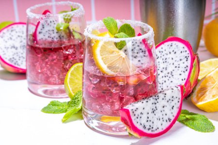 Sweet colorful tropical cocktail with pitaya or dragon fruit, lime and mint. Salted margarita alcohol pitahaya fruit drink over light tile background copy space 
