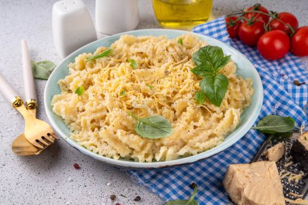 Mafaldine pasta with white sauce, italian bechamel, creamy cheese sauce pasta on white concrete background, with ingredients and spices, copy space