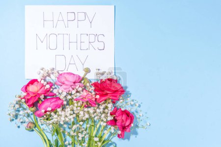 Moms day greeting card, invitation background, Spring bouquet of beautiful ranunculus flower, with cute craft paper gift bow and note Happy Mothers day, copy space on white background