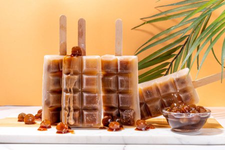 Tapioka latte popsicles. Frozen tapioca boba balls coffee frappe, ice cream lollypops made with asian cold tapioca coffee, with coconut cream and caramel sauce
