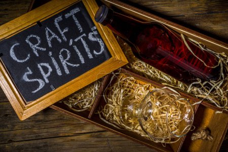 Craft Spirituosen Alkohol. Verschiedene Flaschen und Gläser mit handgefertigten harten starken Alkoholgetränken. Alte hölzerne rustikale Hintergrund Kopierraum