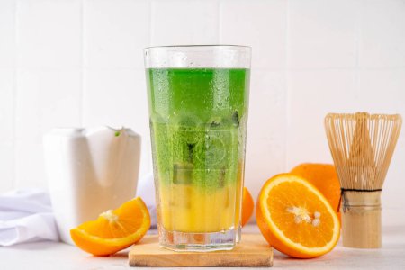 Orange Matcha Limonade, Kalter asiatischer Fruchtcocktail mit grünem Matcha und orangefarbenem Zitrusgetränk auf weißem Hintergrund, Leerzeichen kopieren
