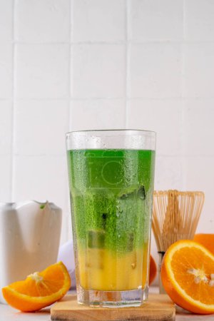 Orange Matcha Limonade, Kalter asiatischer Fruchtcocktail mit grünem Matcha und orangefarbenem Zitrusgetränk auf weißem Hintergrund, Leerzeichen kopieren
