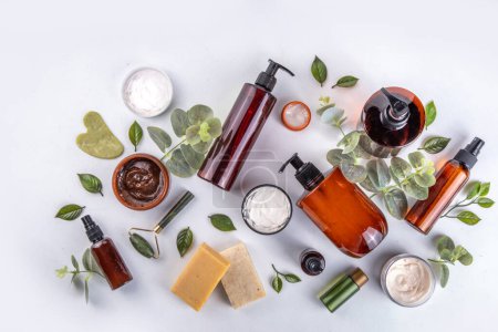 Natural organic skin care flat lay. Natural organic beauty cosmetic products on white background: hand lotion, face cream in jar, essential oil, skin roller, with eucalyptus and tea tree leaves