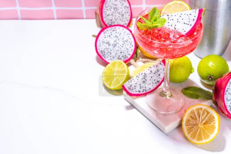 Sweet colorful tropical cocktail with pitaya or dragon fruit, lime and mint. Martini alcohol pitahaya fruit drink over light tile background copy space 