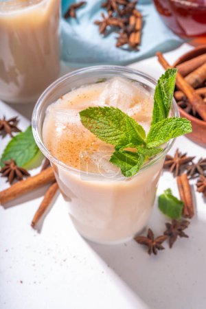 Thai Iced tea, asian indian masala spices drink with non-dairy coconut whipped milk, ice cubes and mint leaves, copy space