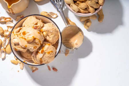 Téléchargez les photos : Des boules de glace au beurre d'arachide. Beaucoup de noix gelato cuillères dans un bol en céramique, avec sauce caramel, blanc cuisine espace de copie de fond - en image libre de droit