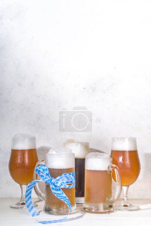 Oktoberfest various beer glasses and mugs with pretzel, wheat and hops. Bar and pub menu, invitation card background on white wooden background copy space