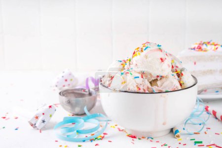 Helado de pastel de cumpleaños. Tazón porción de pastel de cumpleaños sabor helado de vainilla blanca con coloridos espolvoreos de azúcar, funfetti con decoraciones de cumpleaños felices en la mesa, espacio de copia