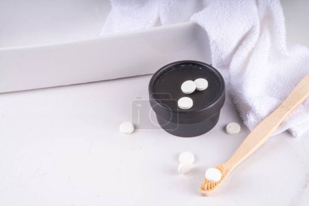 Zahnpasta Tabletten auf Zahnbürste, weiße feste Zahnpasta Tablette mit Bambus-Zahnbürste auf modernen weißen Badezimmerhintergrund