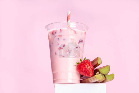 Strawberry rhubarb milkshake, frozen creamy cocktail drink with whipped ice cream, rhubarb and sliced strawberries copy space