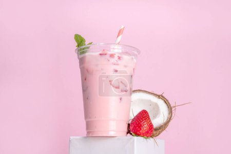 Strawberry coconut milkshake, frozen creamy cocktail drink with coconut milk and whipped sliced strawberries copy space