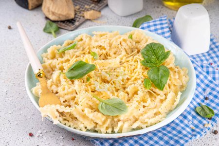 Mafaldine pasta with white sauce, italian bechamel, creamy cheese sauce pasta on white concrete background, with ingredients and spices, copy space