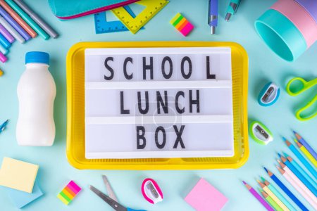 Gesunde Schulmahlzeit, Kinder packen Lunchpaket mit Obst, Beeren, Nüssen und Sandwich mit Gemüse. Kinder-Diät-Snack-Essen mit Schulbedarf, hellblauer Hintergrund von oben Ansicht Kopierraum