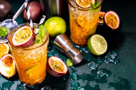 Sweet colorful tropical cocktail with passion fruit, lime and mint. Long boozy alcohol passion fruit drink over dark background copy space