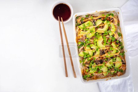 Photo for Philadelphia Sushi Bake Recipe Casserole made with Rice, cream cheese, salmon trout, seaweed, avocado, sauce, green onion. Served with toasted nori sheets likea taco - Royalty Free Image