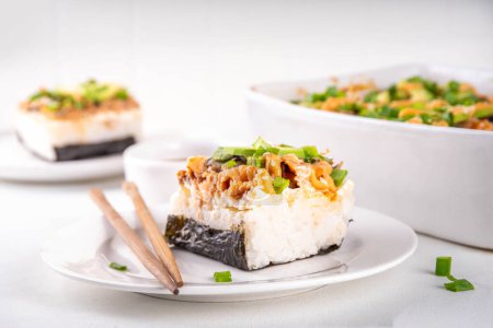 Filadelfia Sushi Bake Recipe cazuela hecha con arroz, queso crema, trucha de salmón, algas marinas, aguacate, salsa, cebolla verde. Servido con tostadas hojas de nori como taco