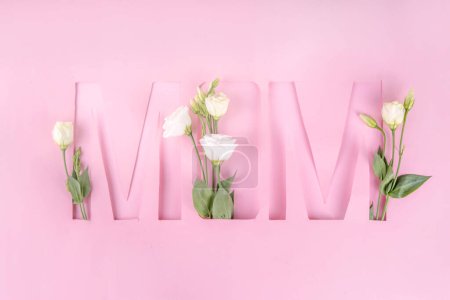 Photo for Mother's day international holiday greeting card , on pink background with flowers. Frame  cut out inscription word MOM with daisies, rose bouquet, flat lay top view copy space - Royalty Free Image