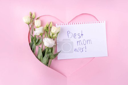 Photo for Mother's day international holiday greeting card , on pink background with flowers. Cut out heart shaped frame with rose bouquet, flat lay top view copy space - Royalty Free Image