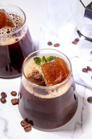 Café froid Espresso Carajillo Cocktail avec glaçons expresso congelés, café noir fort, liqueur et vodka, sur fond de table de cuisine blanche espace de copie