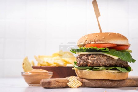 Photo for Tasty beef meat burger  with potato chips and burger sauce, Tasty homemade cheeseburger with cutlet, cheese and vegetables, mouth-watering delicious food on white background copy space - Royalty Free Image