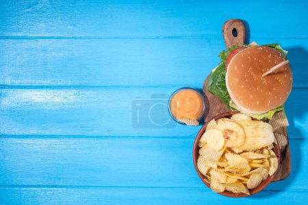 Photo for Tasty cheeseburger, chips and sauce with patriotic american flag. July 4th, Independence day picnic party food, usa themed  bbq hamburger copy space - Royalty Free Image