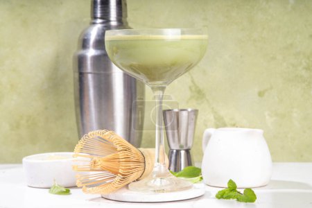 Téléchargez les photos : Cocktail crémeux matcha martini Matchatini, cocktail d'été froid tendance. Matcha sans alcool mocktail ou cocktail d'alcool, dans des verres à martini à la poudre de matcha vert, avec fond clair - en image libre de droit