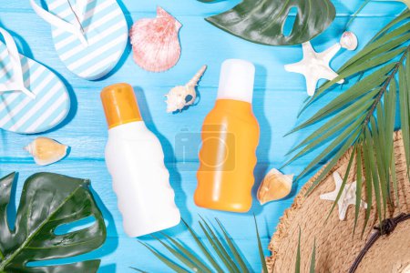 Suntan cream bottle mockup, beach bag, female hat, flip-flops and tropical leaves on colorful bright background. Sun protection, Sunblock  cream bottle, summer vacation concept 