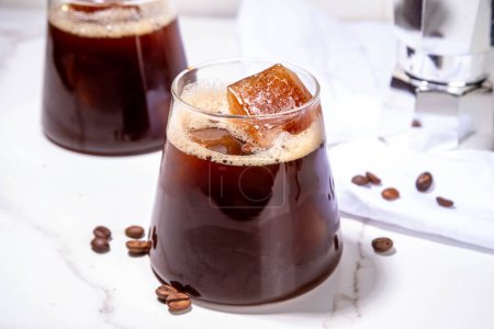 Cold Brew Coffee Espresso Carajillo Cocktail mit gefrorenen Espresso-Eiswürfeln, starkem schwarzen Kaffee, Likör und Wodka, auf weißem Küchentisch