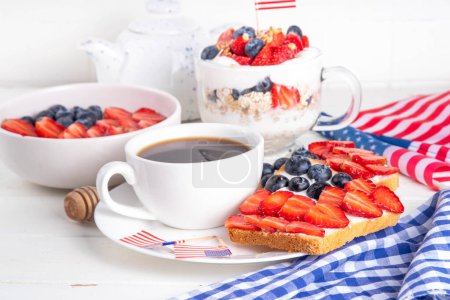 USA patriotic breakfast or brunch with american flag decorated oatmeal, layered yogurt granola dessert, toast sandwiches with fresh berries, and coffee cup on kitchen garden table